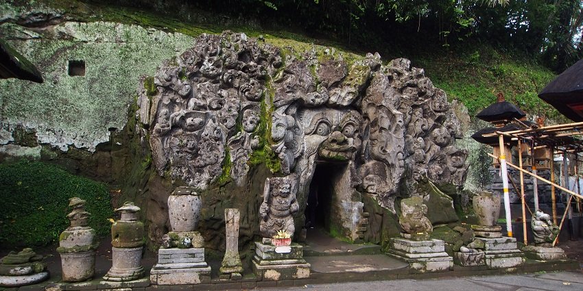 Intricately carved walls of the cave surrounded by green moss covered rocks
