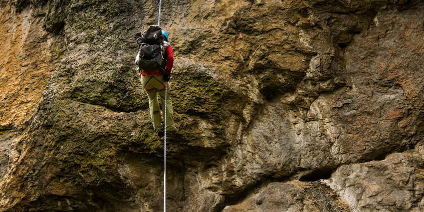 Climber scaling a rugged rock and enjoying rock climbing, a must-try thrilling activity.