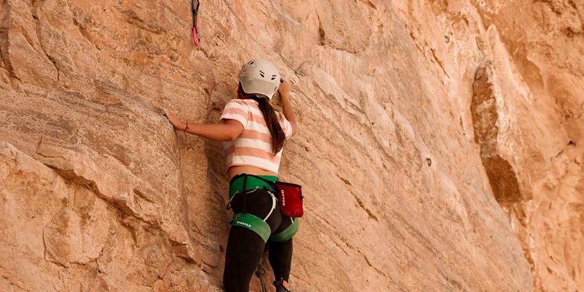 View of a climber climbing a big rock, part of a mountain for an exhilarating experience.