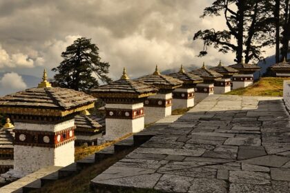 Traditional Bhutanese architecture with a stupa and mountains in the background.