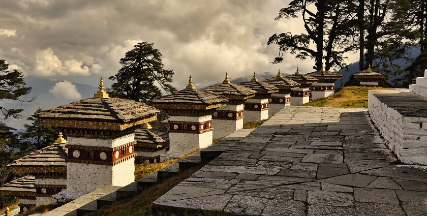 Traditional Bhutanese architecture with a stupa and mountains in the background.