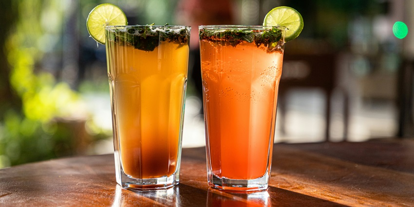 A picture of a bar counter with 2 glasses of cocktails placed on, decorated with lime