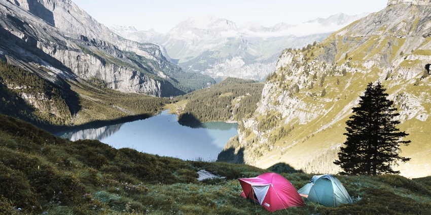 Tents set up in a scenic mountainous area with lush green grass in the background.