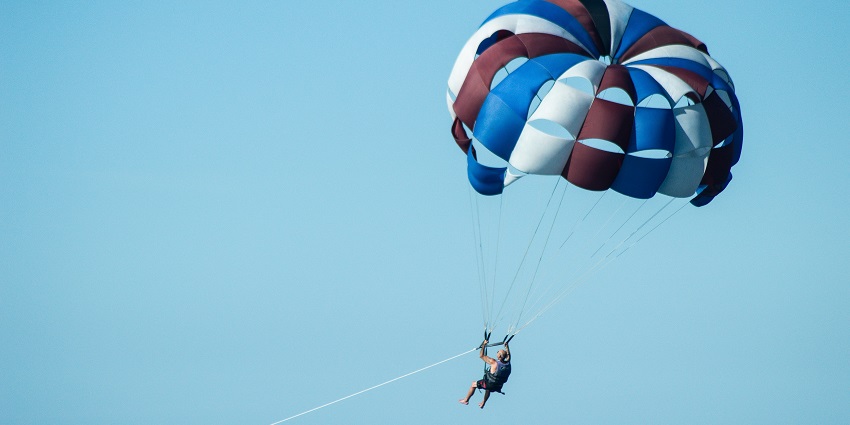 Stunning view of a man enjoying an adventure activity with a parachute in clear blue sky.