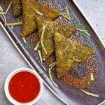 A glimpse of delicious samosas being served on a plate with tangy red chilli chutney.