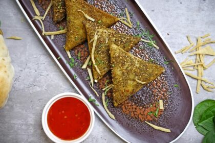 A glimpse of delicious samosas being served on a plate with tangy red chilli chutney.