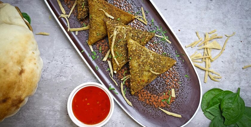 A glimpse of delicious samosas being served on a plate with tangy red chilli chutney.