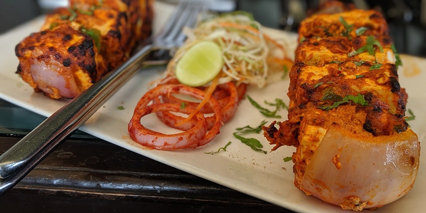 Aromatic paneer tikka and smoky tandoori dishes sizzling on the grill, tempting your senses