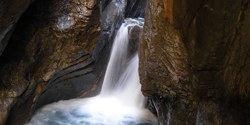 A picture of a majestic waterfall cascading down a rocky terrain, forming a river branch