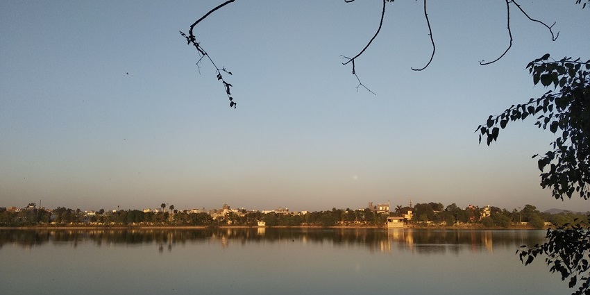 Image of a Lake similar to Sangram Sagar with walking paths, trees, and scenic water views.