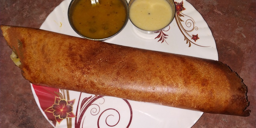 Butter dosa served on a plate with chutney and sambar, a popular South Indian dish.
