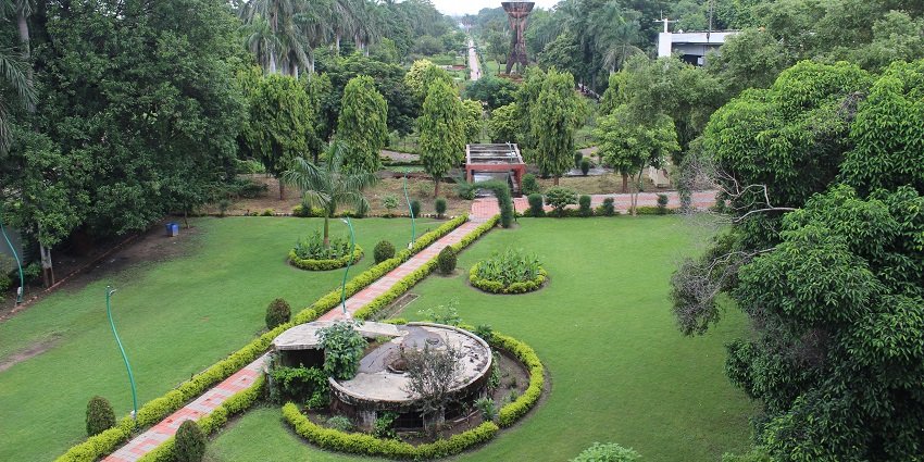 Picturesque view inside a park, with lush gardens and trees, vibrant flowerbeds and shrubs