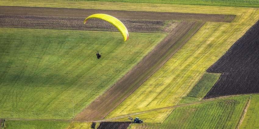 A man enjoying his beautiful green land view while paragliding - one of the best paragliding spot in Gujurat