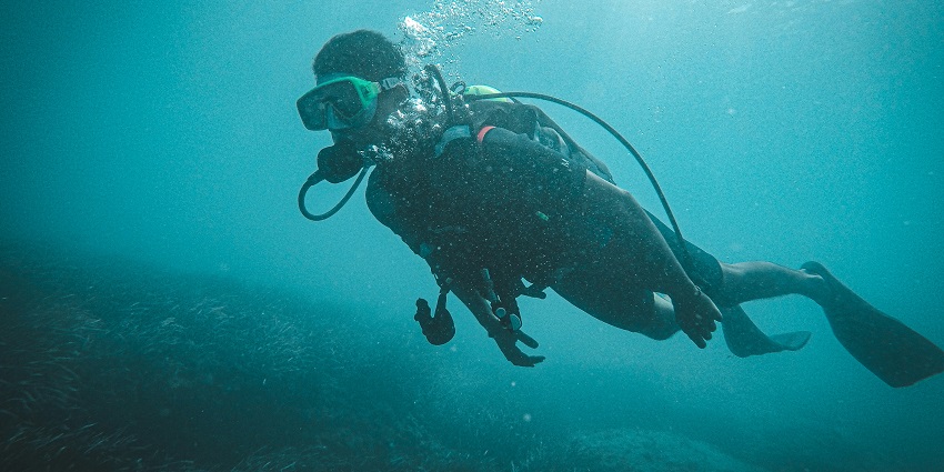 A person scuba diving underwater, one of the famous Sinquerim Beach water sports.