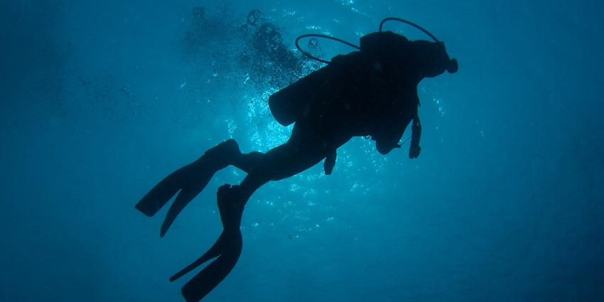 A diver in silhouette showcasing the sea around in the Layang-Layang region.