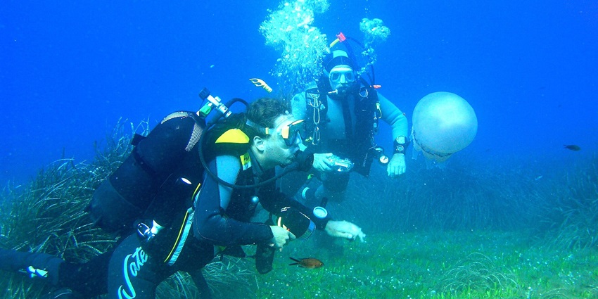 Scuba divers enjoying the water sports under the vast waterbody with beautiful marine views.
