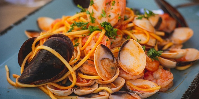 Delicious plate of pasta topped with clams and shrimp, garnished with herbs.