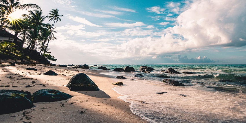 Image of serene seaside view with gentle waves, soft sand, and a clear blue sky.