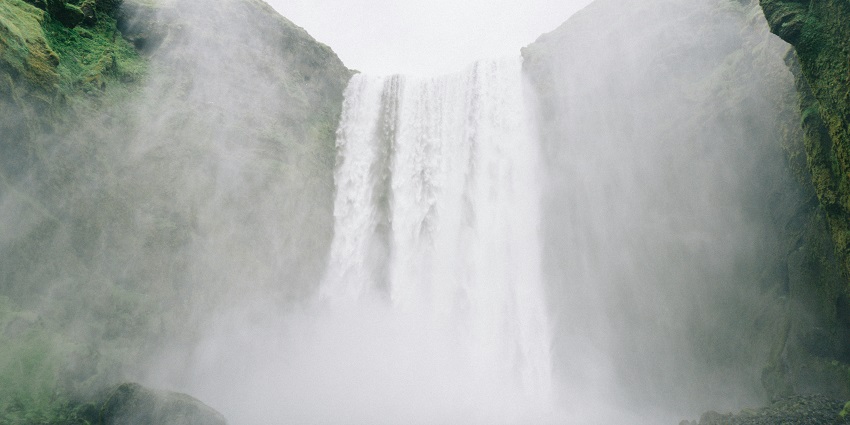 A mesmerising view of a waterfall surrounded by lush greenery during the daytime.