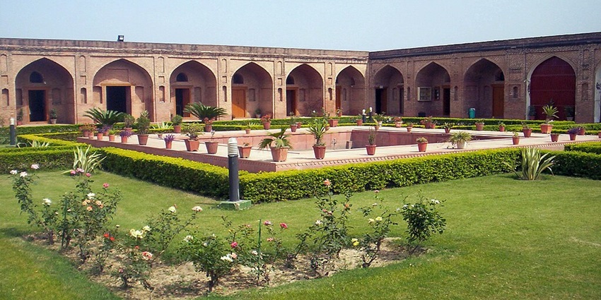 Image of Tomb of Sheikh, serene view inside during day time and lush green garden with flowers