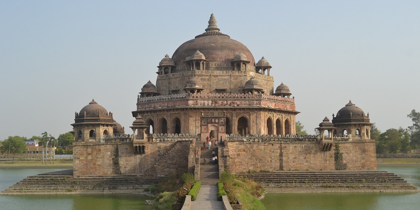 A view of the Sher Shah Suri Tomb located amidst a water body, adding to its allure.