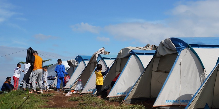 A family campsite with tents, camping chairs, and a picnic table on a grassy field, similar to luxury camping in Kufri.