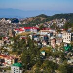 A breathtaking aerial view of Shimla with a lot of houses, mountains and lush greenery.