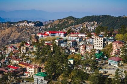 A breathtaking aerial view of Shimla with a lot of houses, mountains and lush greenery.