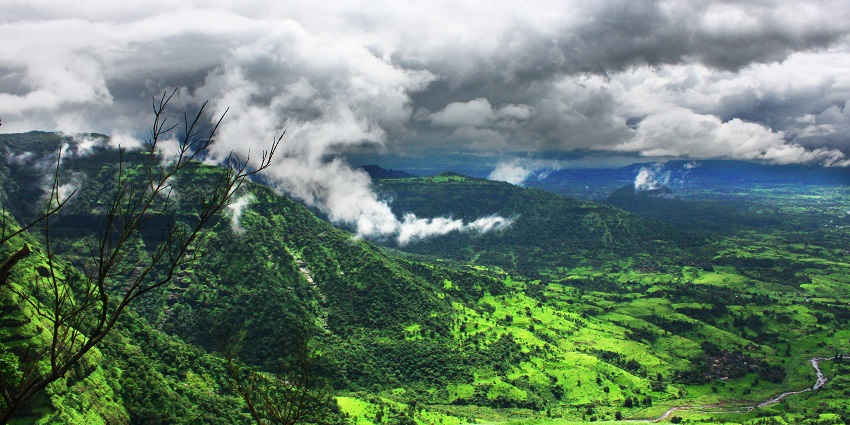 Majestic view of the emerald rolling fields and clouds covering the peaks