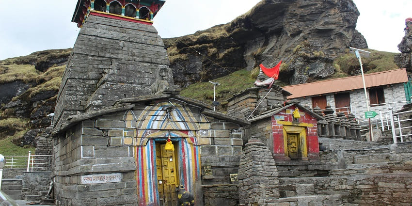 A picture of a temple carved out of rocks and made in a traditional design with a flag hoisted