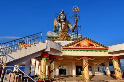 Shiva statue in Pumdikot, reflecting the Shiva temples in Nepal, with a clear blue sky and mountains.