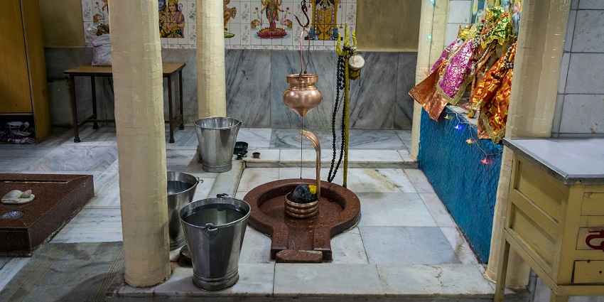 Shivling placed inside a temple, surrounded by traditional offerings and lit oil lamps.