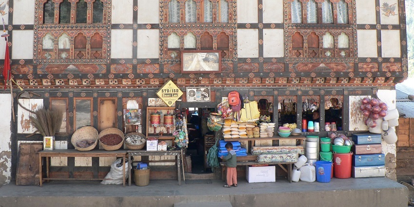 Street scene in Bhutan showing colourful shops and daily life activities, with people walking