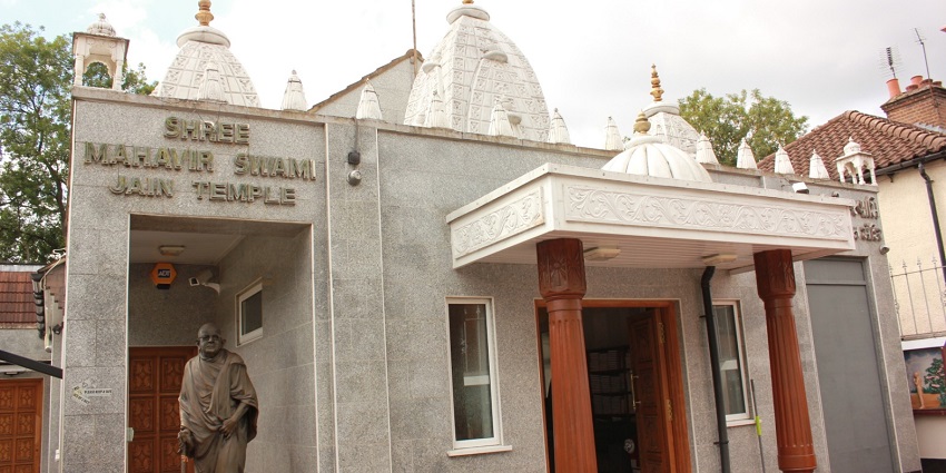A detailed statue is positioned in front of the Shree Mahavir Swami Jain Derasar temple.