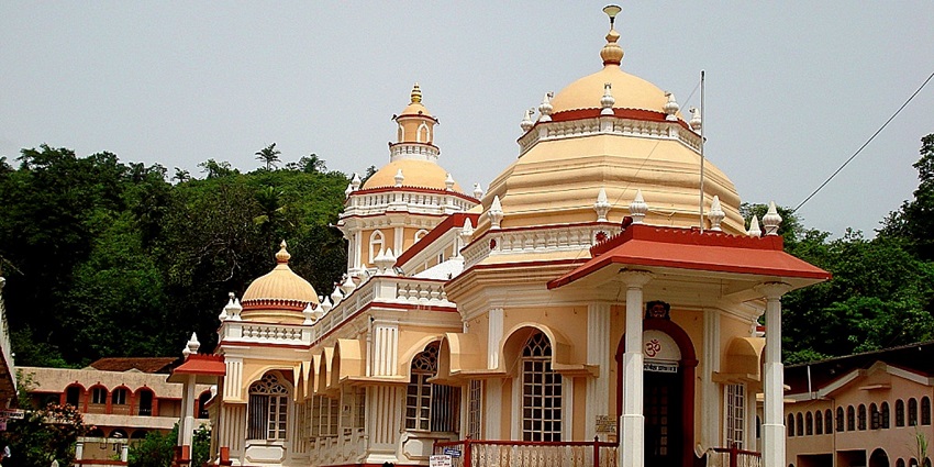A frontal view of a traditionally built Hindu temple, surrounded by a garden