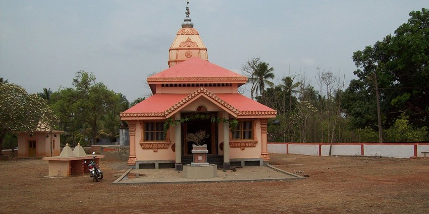 A frontal view of a temple with a traditional Hindu architecture and a garden in front