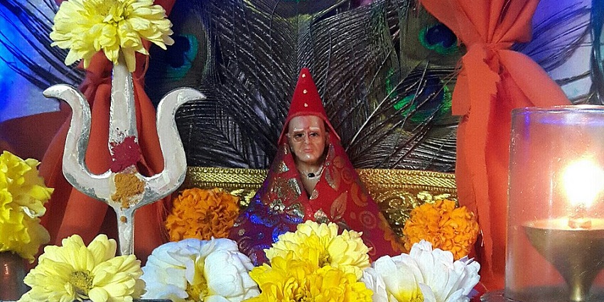 A picture of a prayer sanctum with a decorated idol of a revered Hindu deity placed in the centre