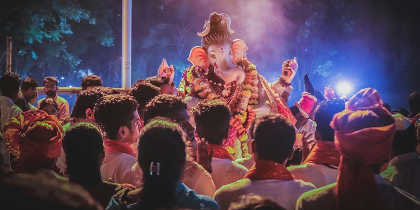 A picture of a religious celebration during nighttime with an Idol of Lord Ganesh on a stage