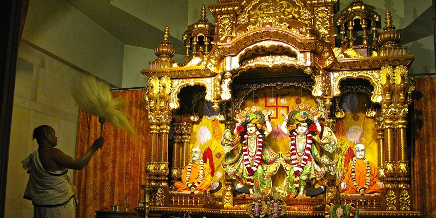 A picture of a priest praying in front of a decorated shrine of Lord Krishna at a temple in Delhi