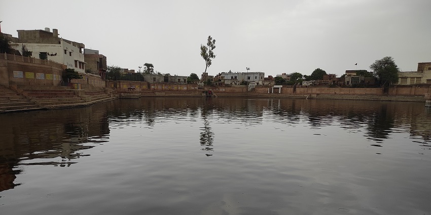 Ruins of an ancient temple beside a serene kund, reminiscent of Shyam Kund in Sikar