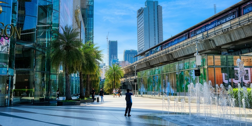 A view of an entrance to the best complex, Siam Paragon with a fountain and people.