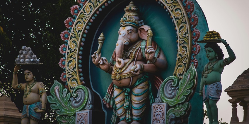 A picture of a statue of Lord Ganesh with a colourful wall in the background