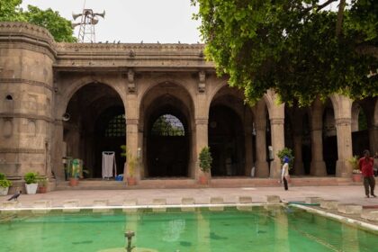 A breathtaking frontal view of Sidi Saiyyed Mosque in Gujarat with a pond in front.