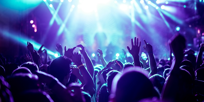 Image of a energetic crowd dancing to the music under the neon lights