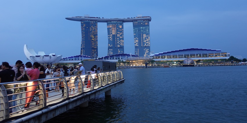 A picture of a scenic cruise ship in a Singapore river with the tall skyline in background