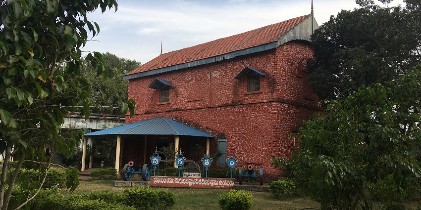 A picture of the exterior of a museum in Rajahmundry, surrounded by lush greenery