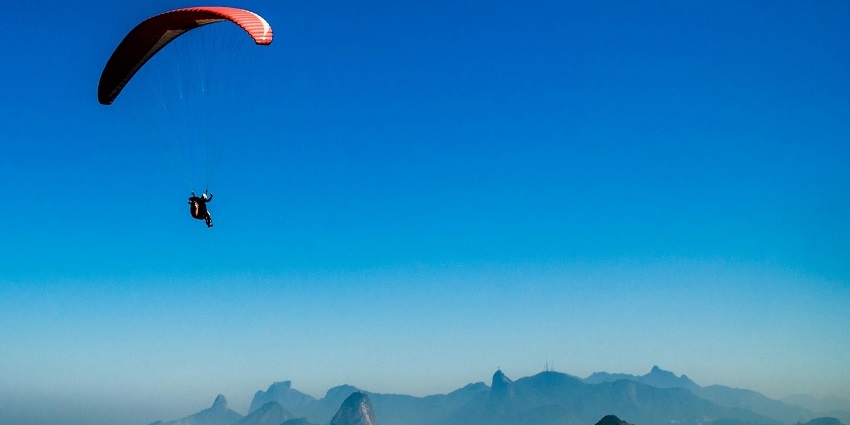 A person paragliding in Nepal under the clear sky while observing the unique landscapes.