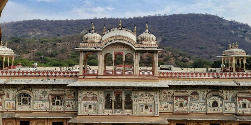 18th-century Jaipur garden features terraced lawns, flowers, Mughal architecture.