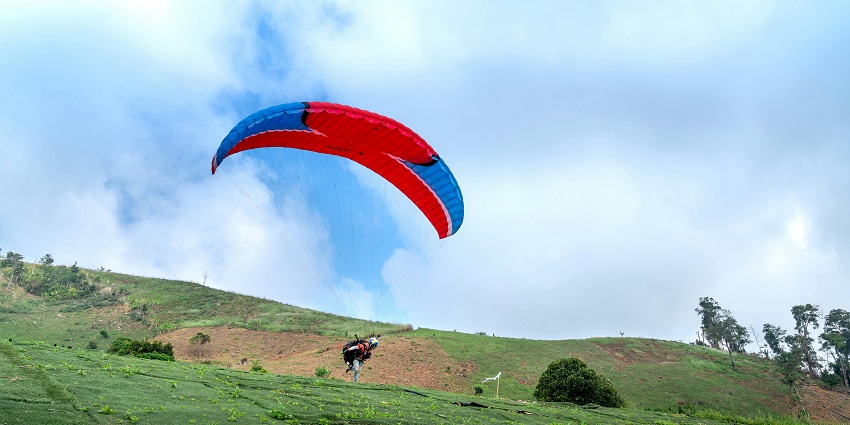 View of a tourist landing on the verdant fields after paragliding at the park