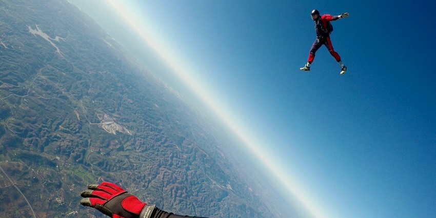 A man geared up in a red suit soaring high up in the air and enjoying scenic views.